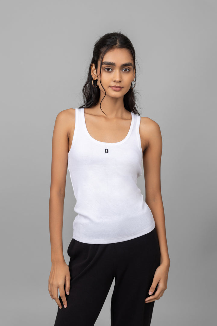 White rib tank top model posing in stylish black pants.