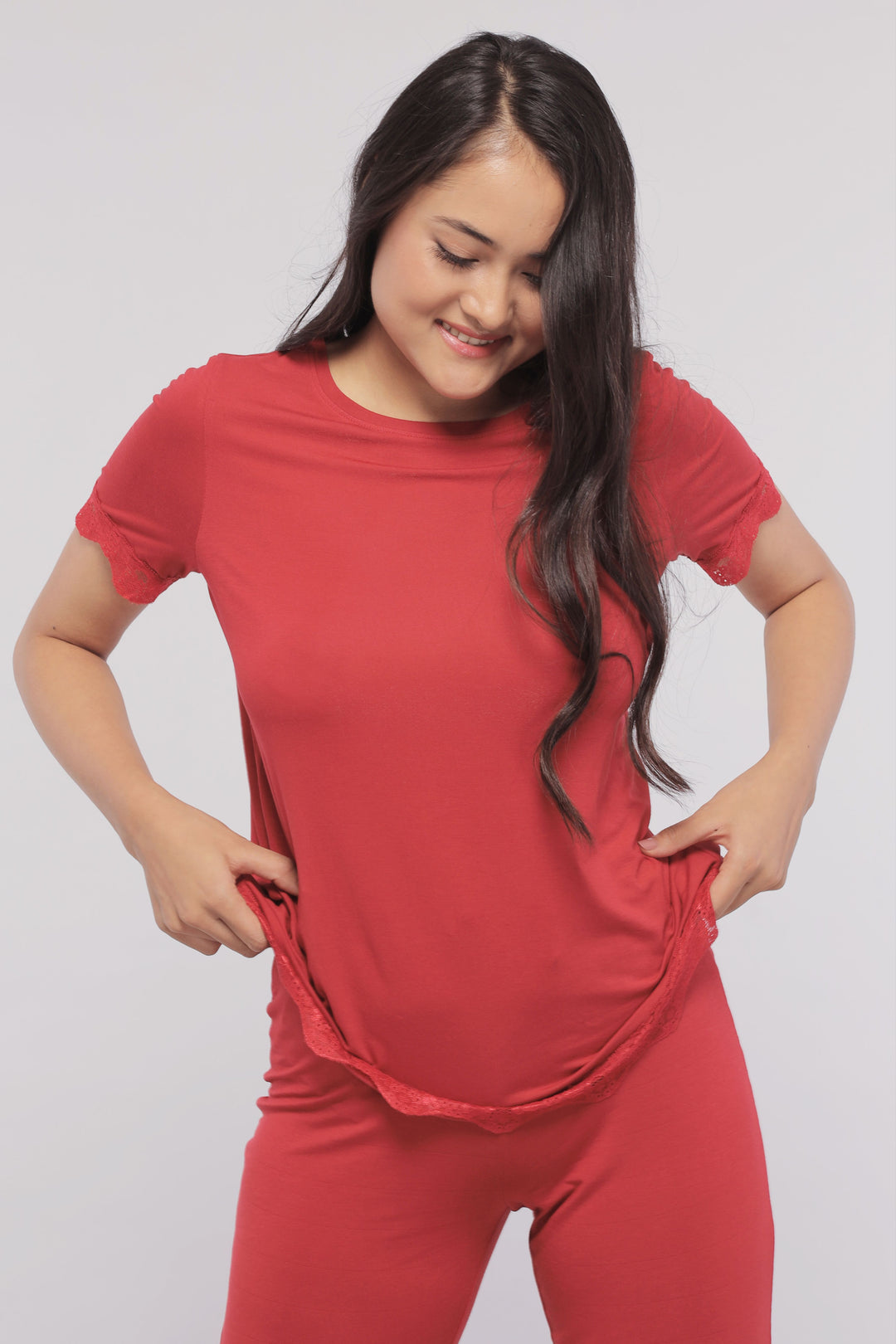 Romantic red lace pajama set worn by smiling woman.