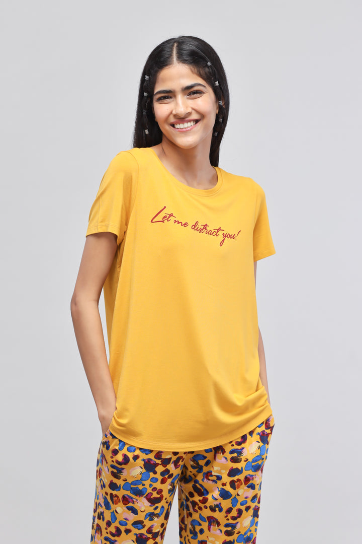 Smiling woman in leopard print pajama set, yellow top with text.