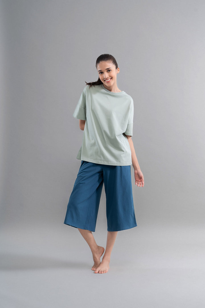 Sage teal cotton culottes worn by a smiling model.