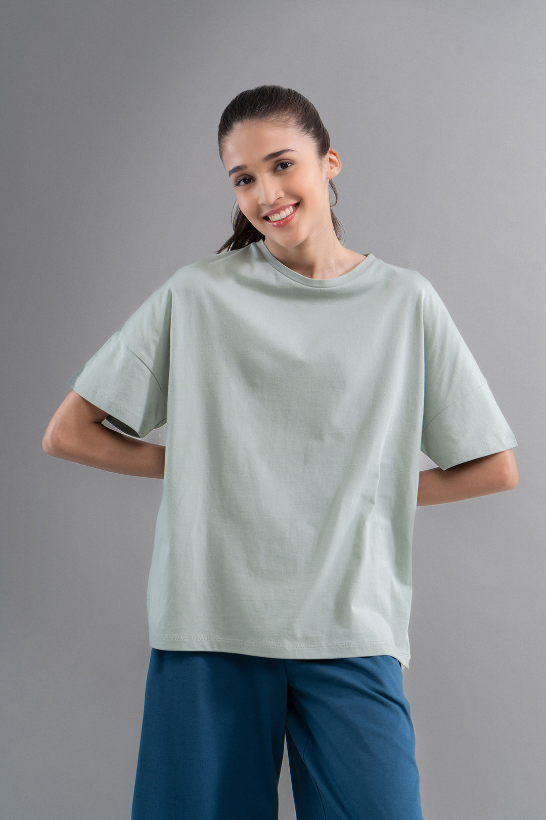 Sage cotton side slit T-shirt worn by smiling model.