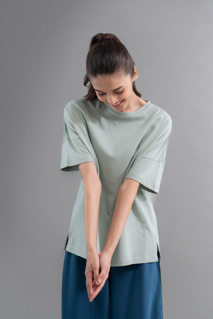 Sage cotton side slit t-shirt worn by a smiling model.