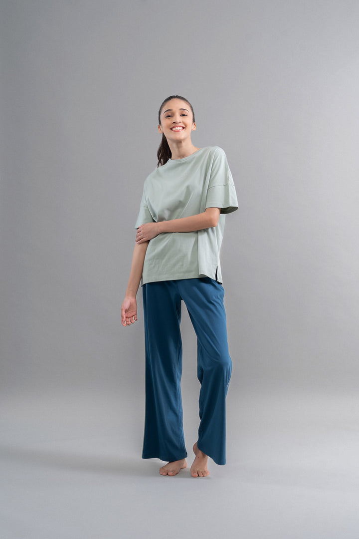 Sage teal cotton lounge pant with contrast piping displayed on model.