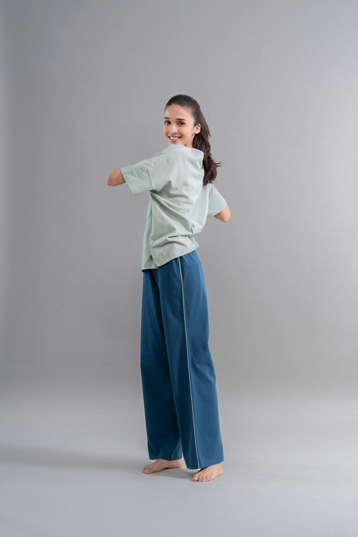 Sage teal cotton lounge pant with contrast piping on model.