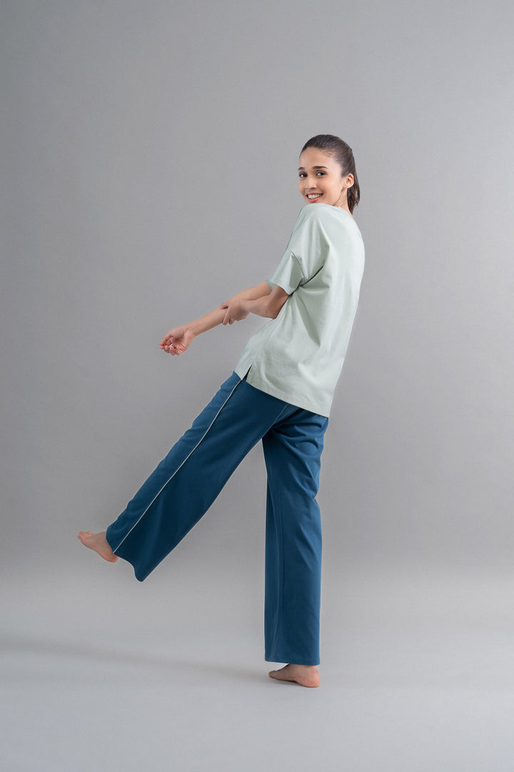 Sage teal cotton lounge pant with contrast piping in casual setting.