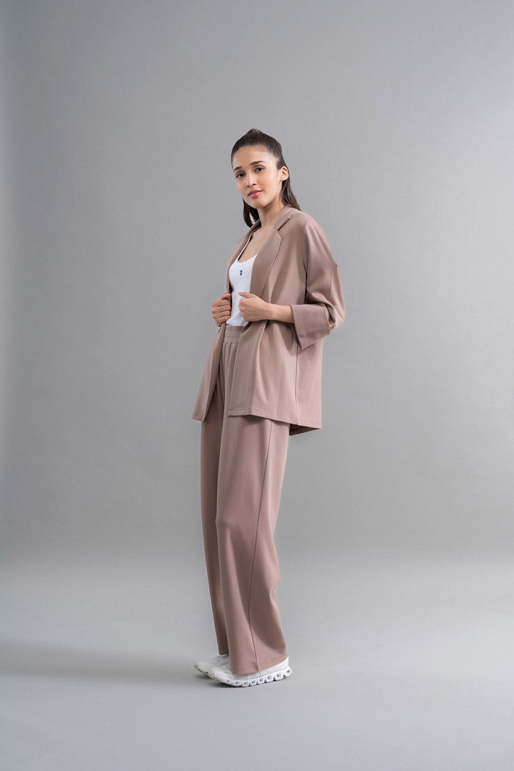 Stylish woman modeling Snugknit® Mocha Blazer Set on gray background.
