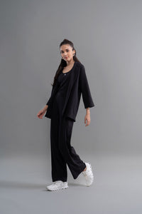 Stylish woman in Snugknit black flared pants, tank top, and blazer.