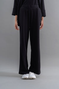 Snugknit® Black Flared Pant worn with white sneakers on a gray background.