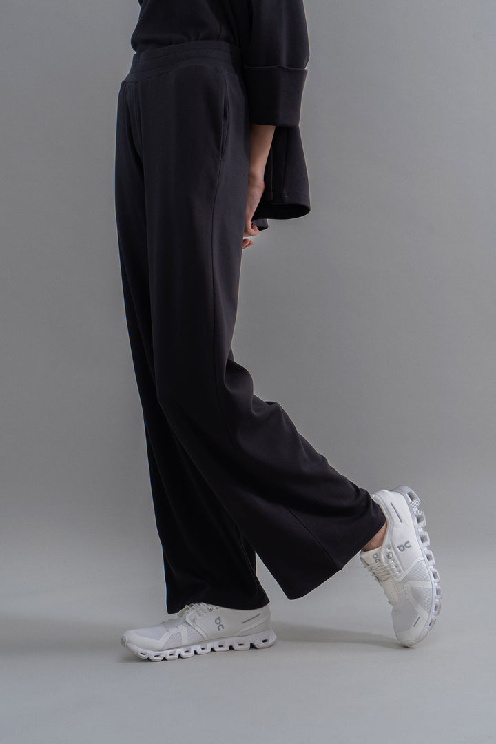 Snugknit® black flared pants styled with white sneakers.