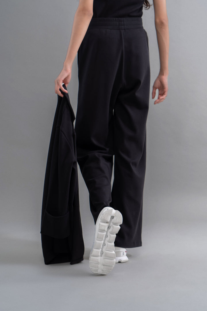 "Model wearing Snugknit® black flared pants with white sneakers."