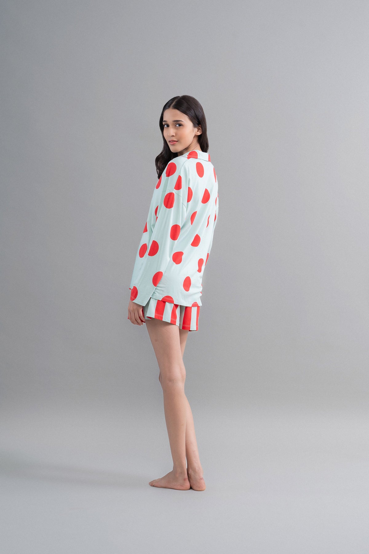 Sage button down shirt with red polka dots on model.