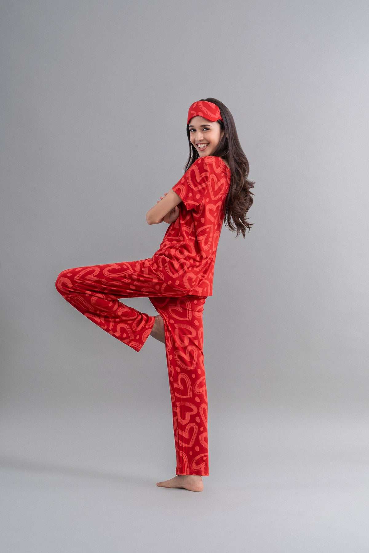 Model in Lovestruck Hearts Red Pajamas, playful pose, vibrant heart design.
