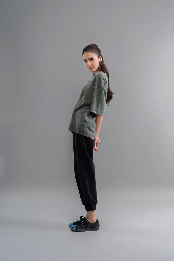 Green acid wash unisex t-shirt modeled by a woman in casual wear.