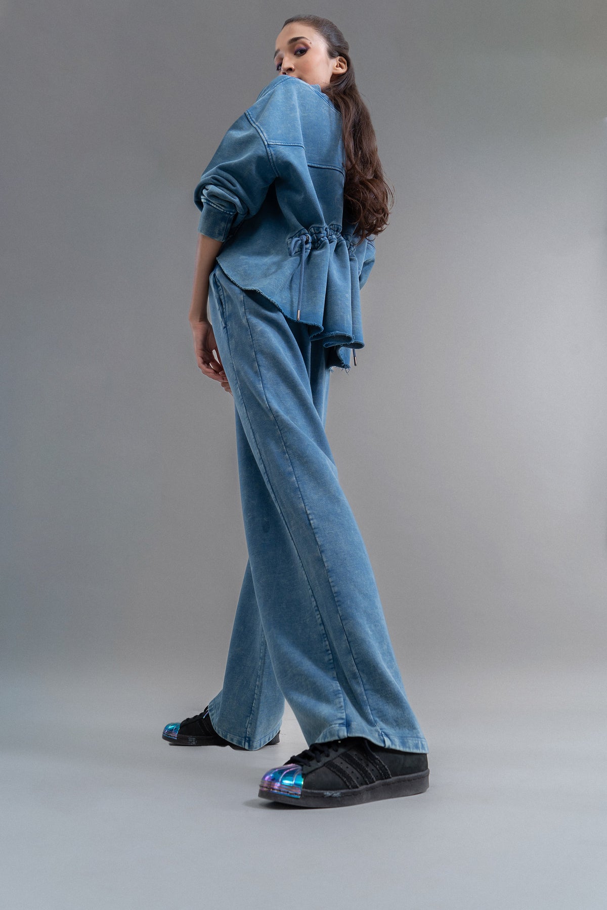 "Model showcasing denim wash cotton terry ruched sweatshirt and stylish pants."