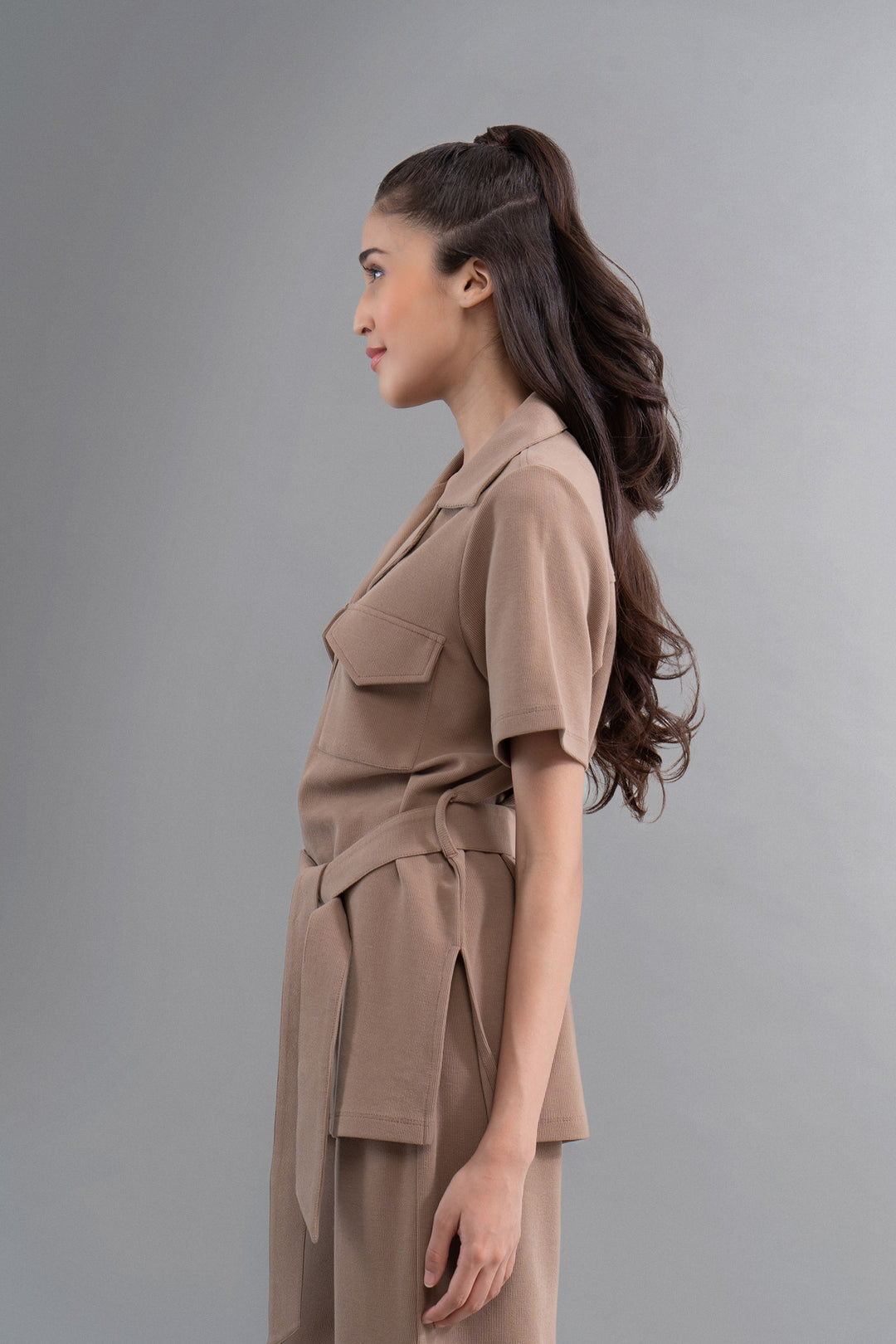 Woman in an earthy brown shirt showcasing modern fashion style.