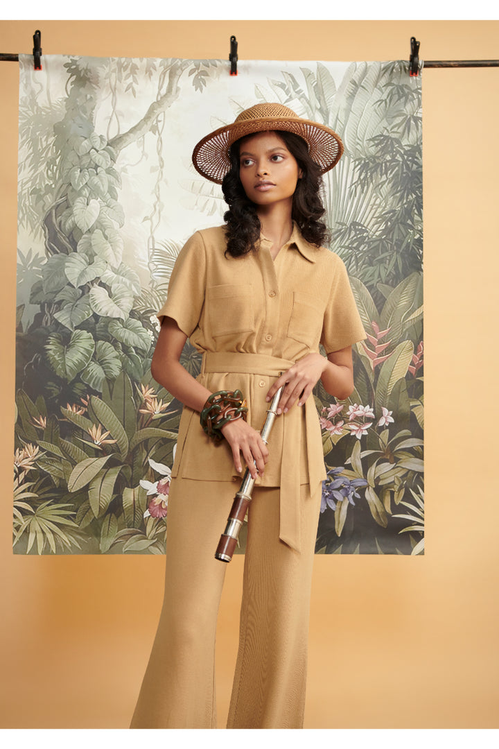 Model wearing mini waffle brown flared pants in a tropical setting.