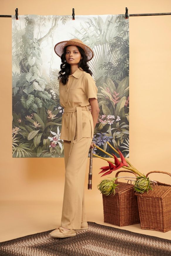 Model showcasing mini waffle brown flared pants with floral backdrop.