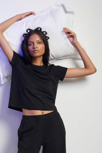 Stylish model wearing a black Supima® T-shirt and matching trousers.