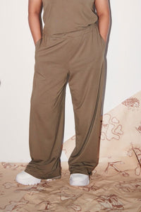 Olive Supima® flared pants styled with white sneakers on a patterned backdrop.