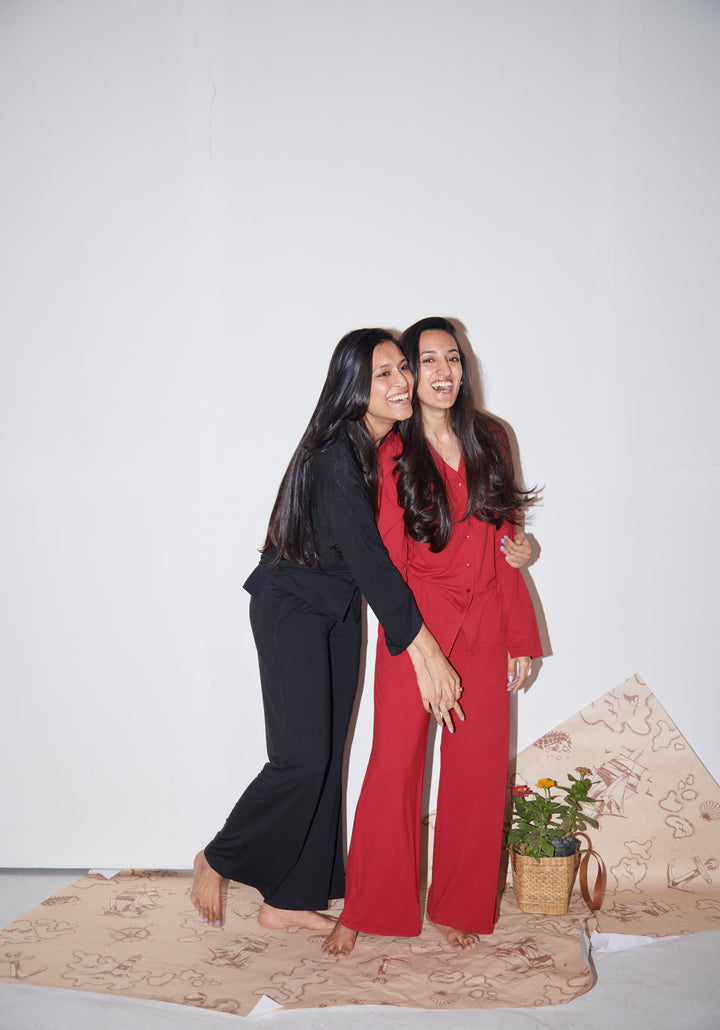 Two women laughing in a black modal button down shirt.