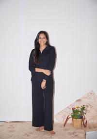 Woman wearing a black modal button down shirt, standing confidently.