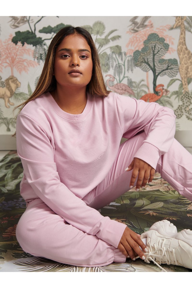 Pink Bamboo Terry Sweatshirt model seated in a stylish floral background.