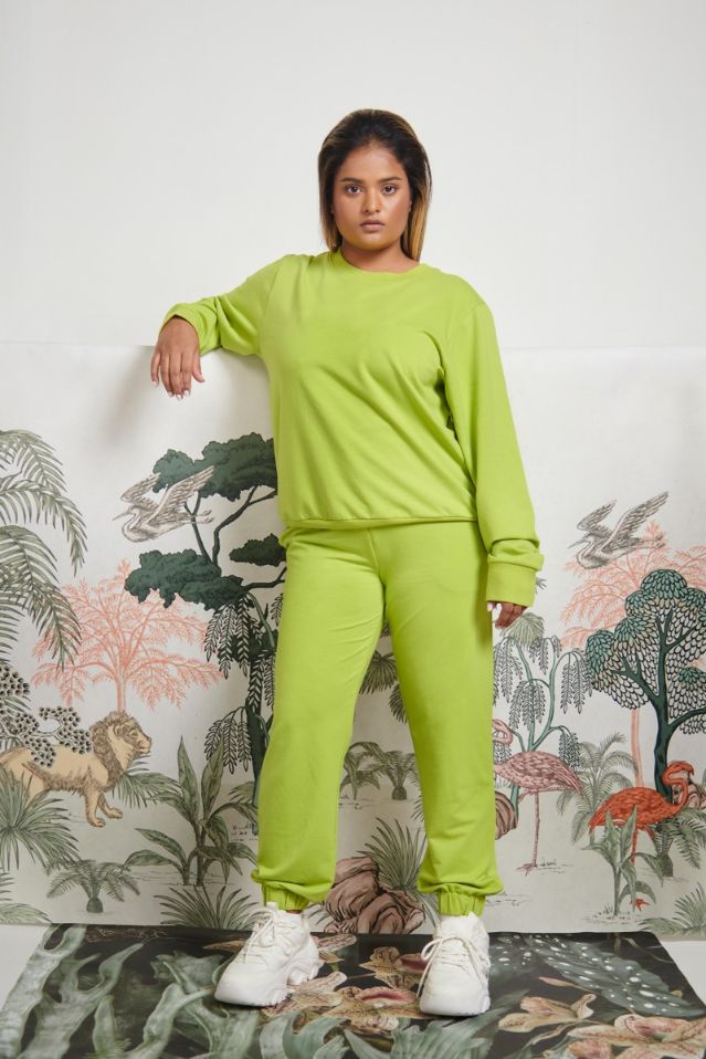 Green bamboo terry sweatshirt model against colorful nature backdrop.