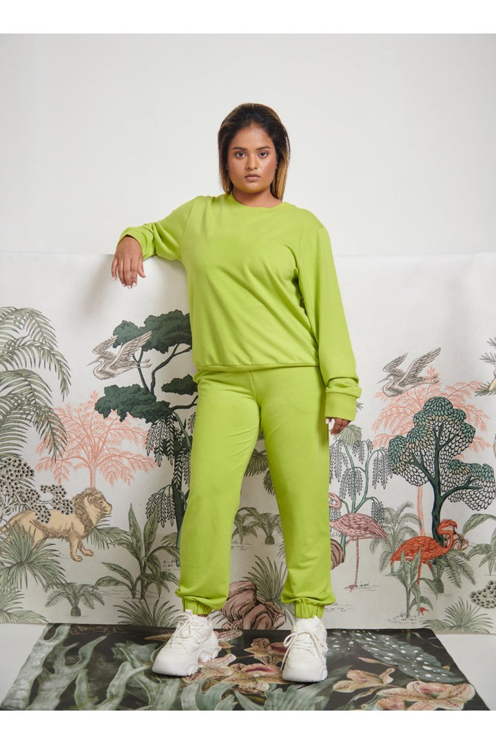 Green bamboo terry sweatshirt model posing against tropical backdrop.