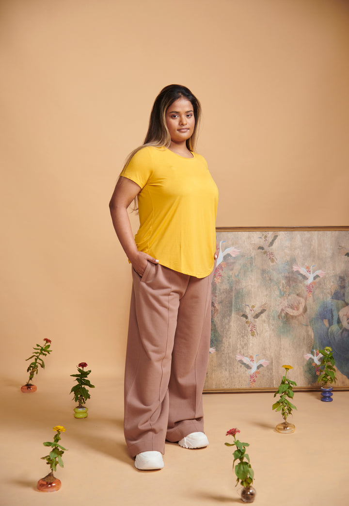 Brown high waist travel pant styled with a yellow top against a neutral background.