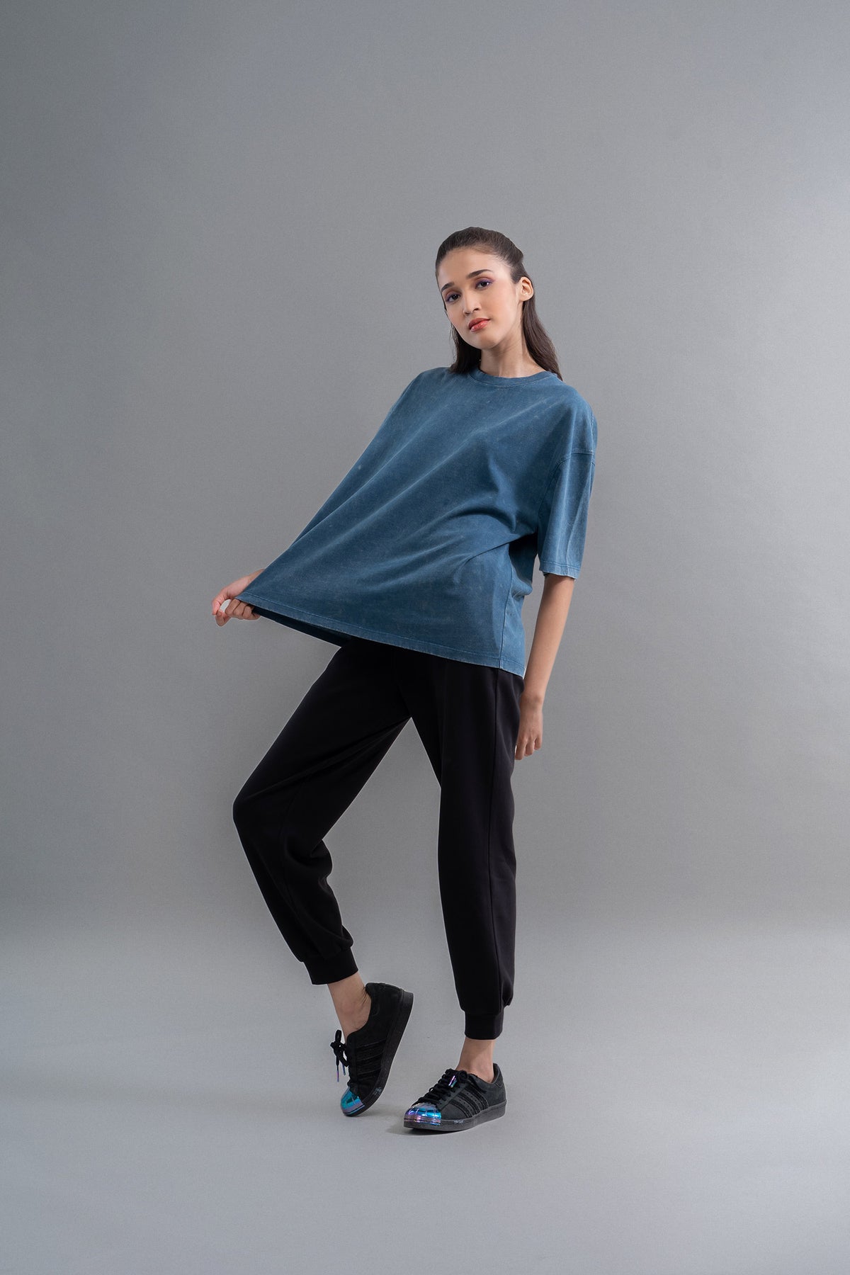 Teal acid wash unisex t-shirt modeled with casual black pants and sneakers.