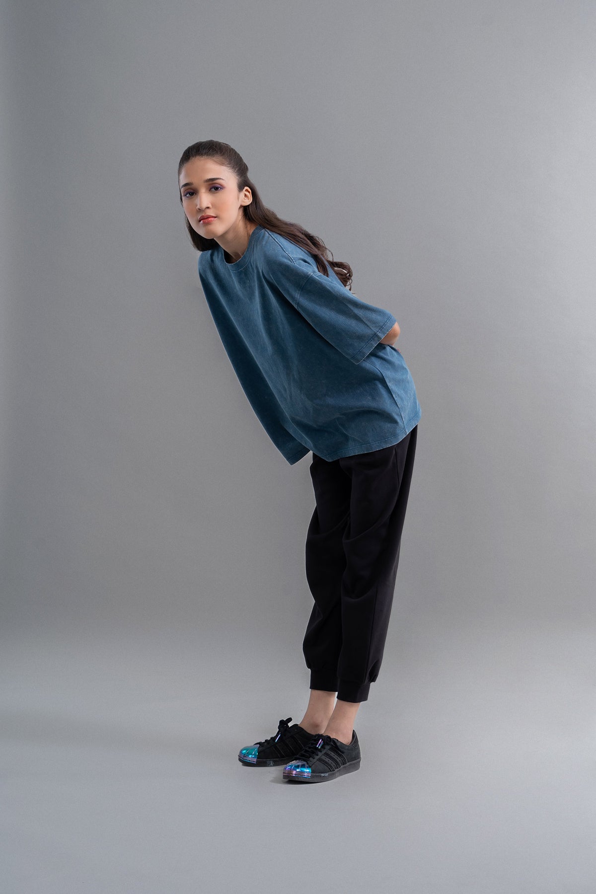 Teal acid wash unisex t-shirt on model with stylish black pants.