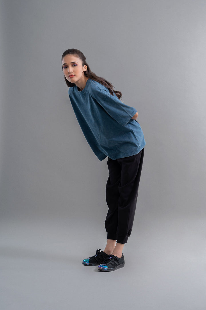 Teal acid wash unisex t-shirt on model with stylish black pants.