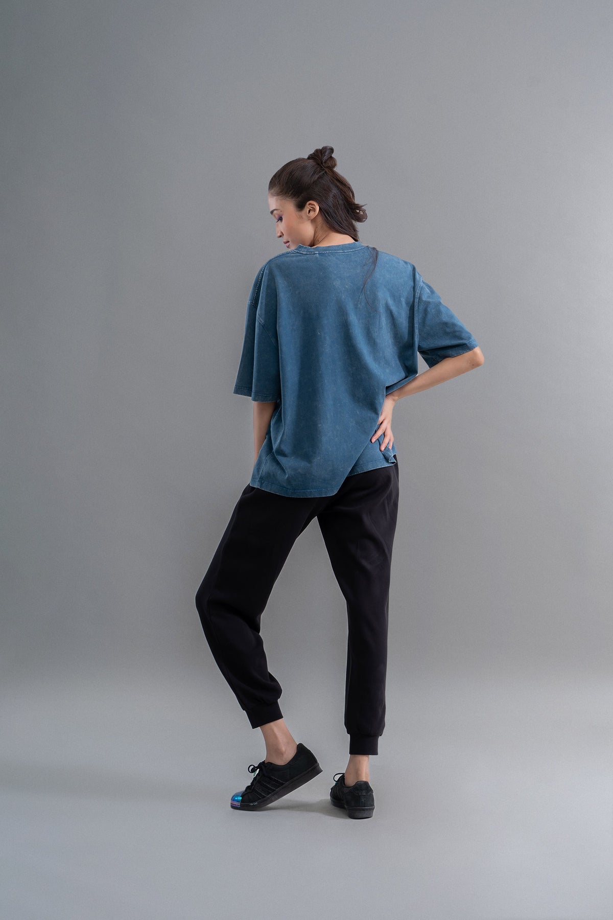 Teal acid wash unisex t-shirt displayed on a model from behind.