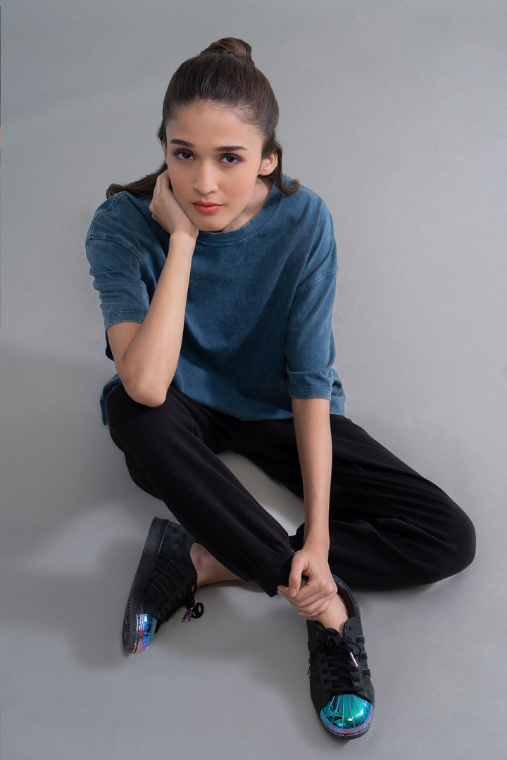 Teal acid wash unisex t-shirt showcased by a model sitting stylishly.