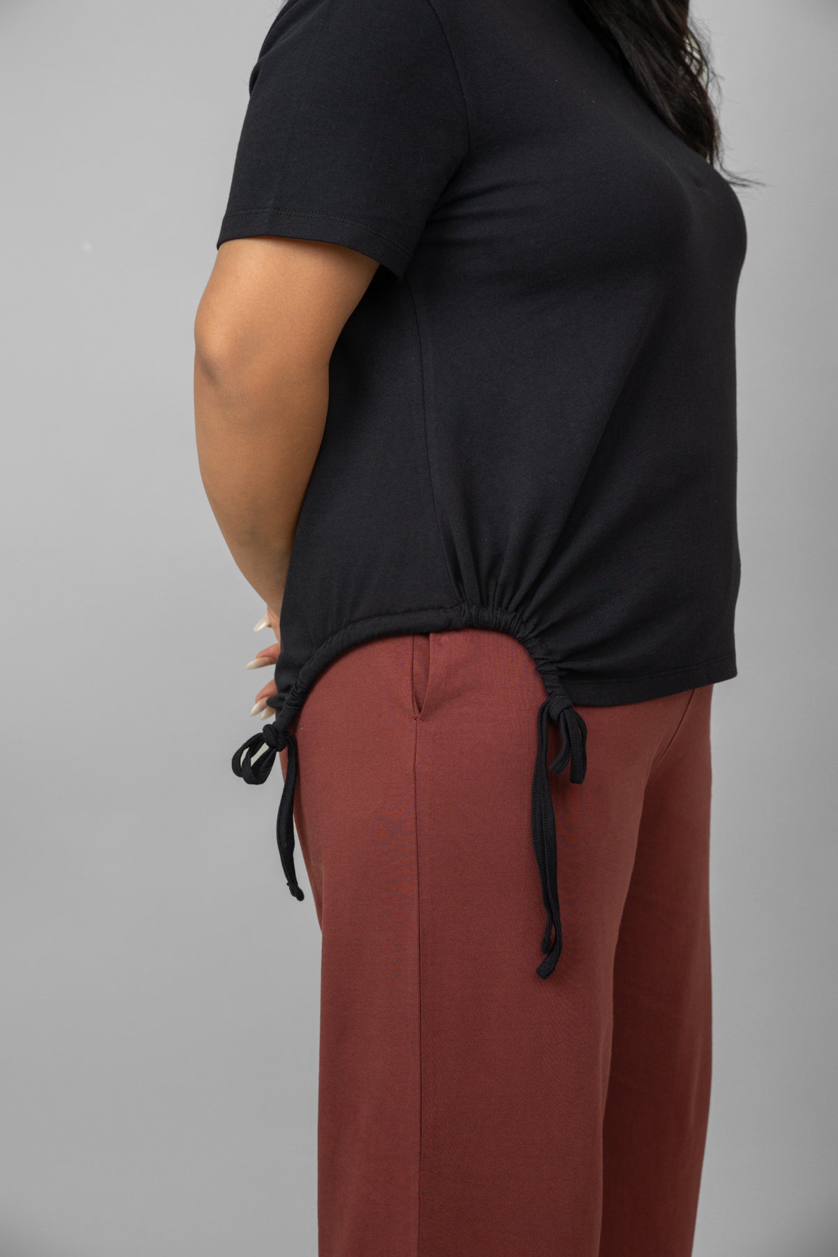 Cotton side ruched black t-shirt styled with loose red pants.