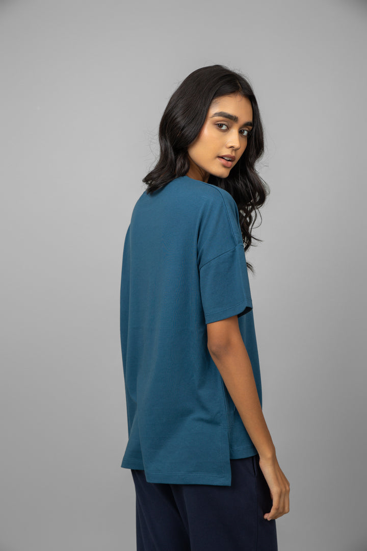 Teal oversized cotton tee displayed on a model from behind.