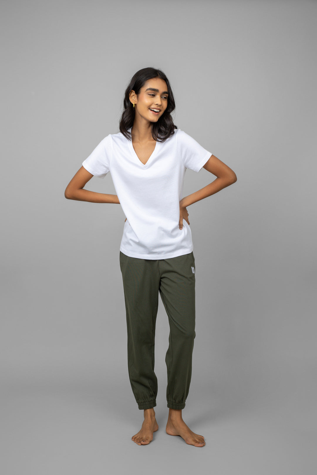 Model wearing a stylish white V-neck tee and green pants.