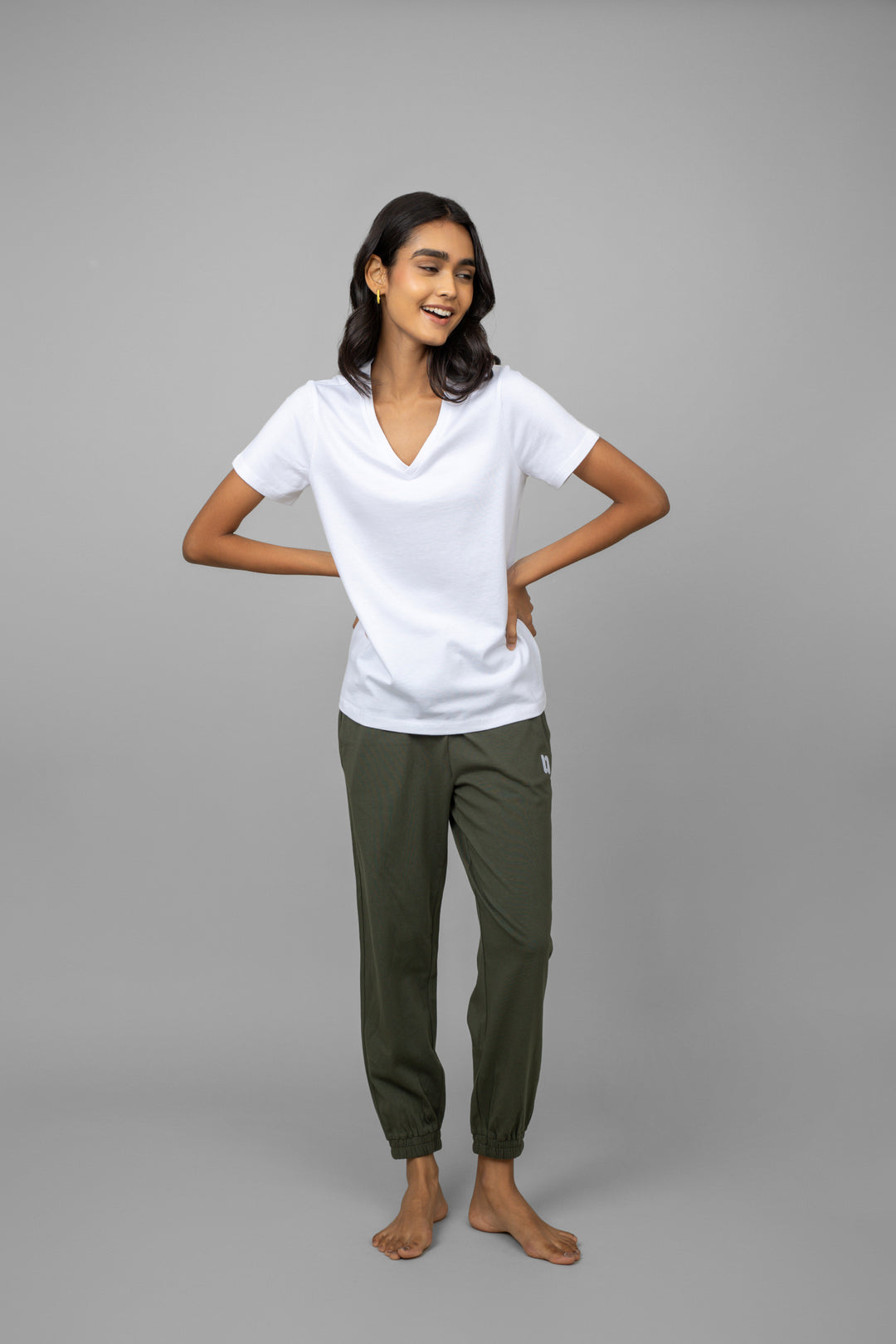 White V-neck jogger set with green pants, model smiling.
