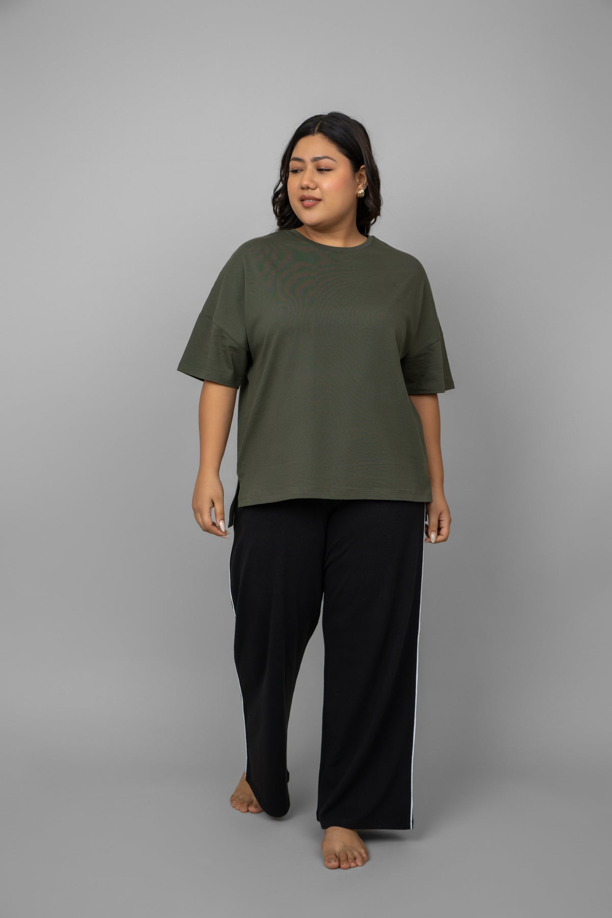 Plus size model wearing black contrast piping pants and green top.