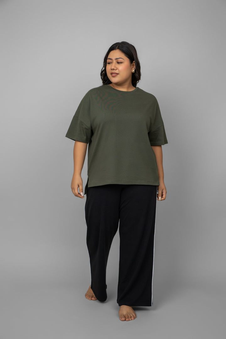 Plus size model wearing black contrast piping pants and green top.