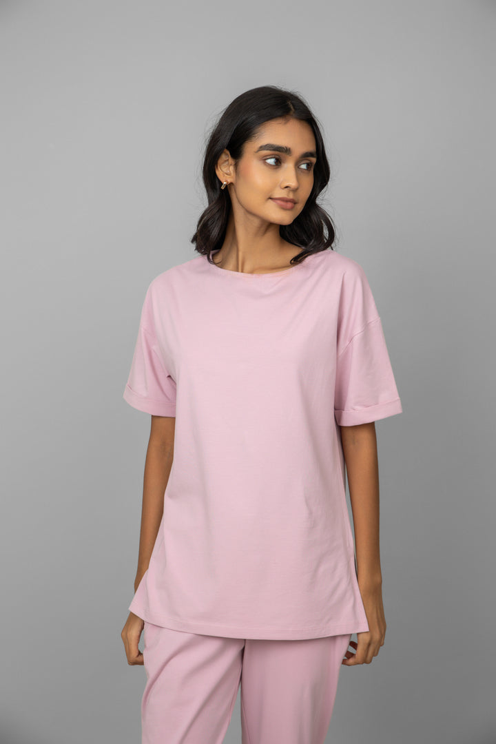Blush pink long top displayed on a model against a gray background.
