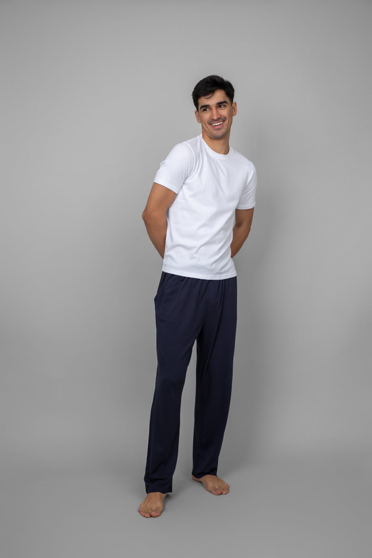 White men's essential t-shirt model posed with navy pants.