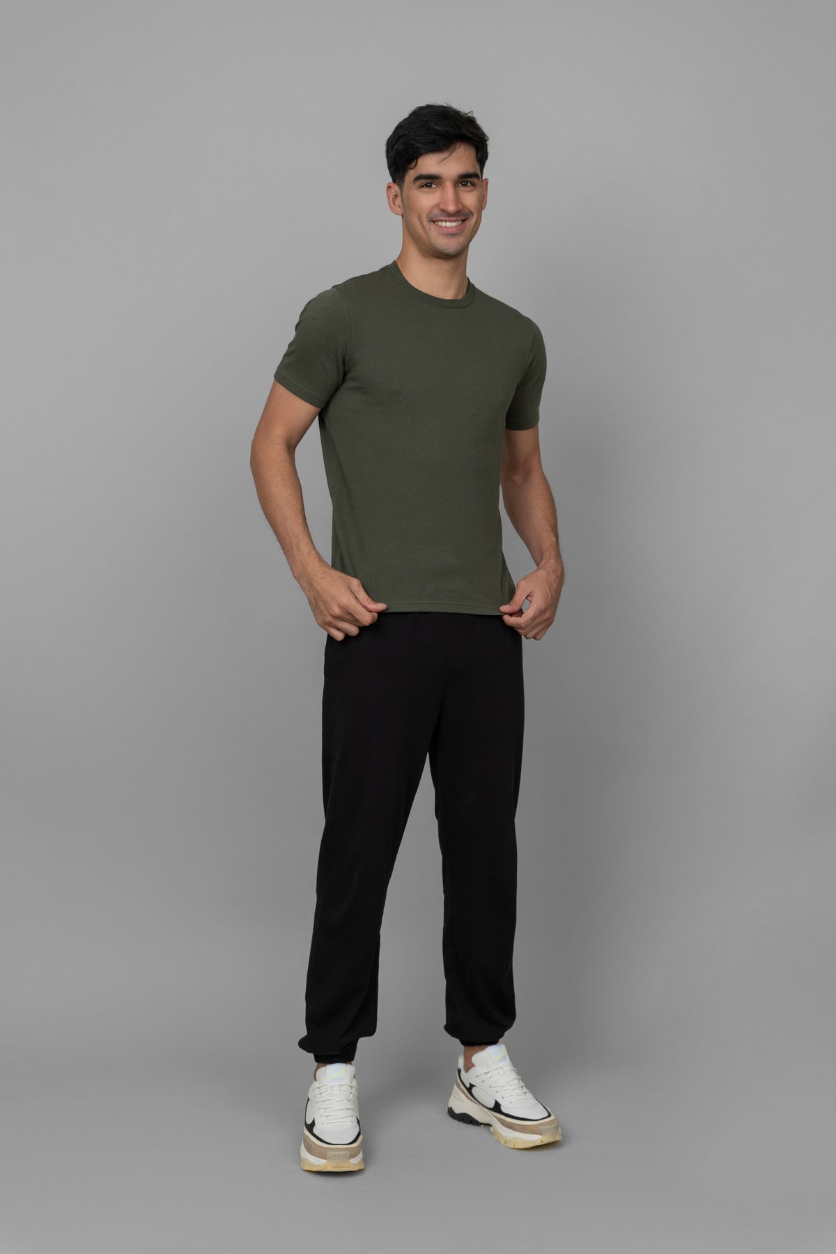Green men's essential t-shirt worn with black pants and sneakers.