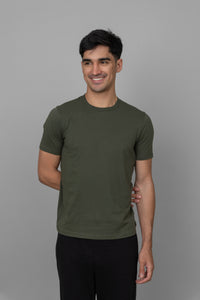 Green men's essential t-shirt on smiling model against gray background.