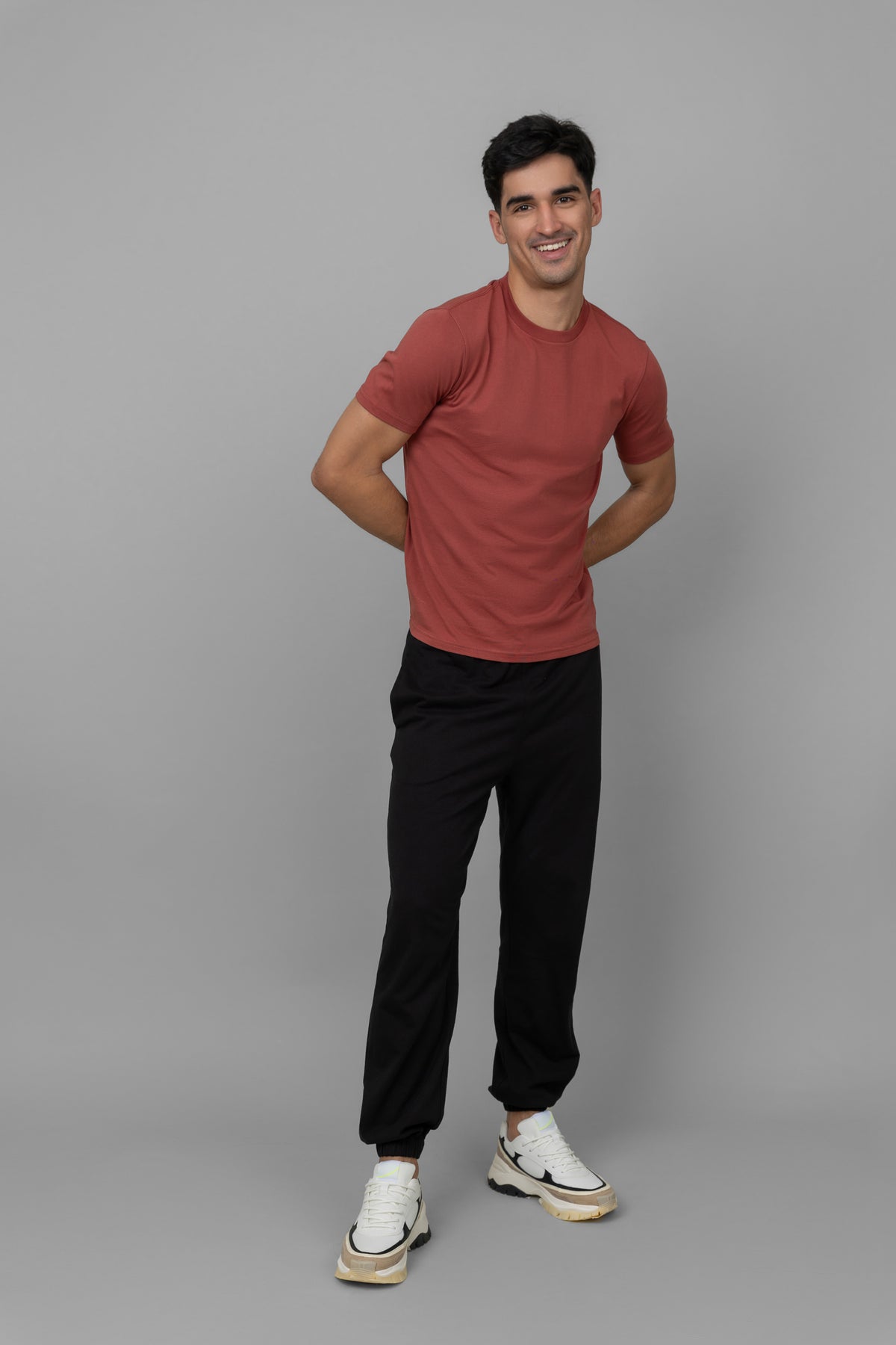 Rust men's essential t-shirt worn by smiling model in casual attire.