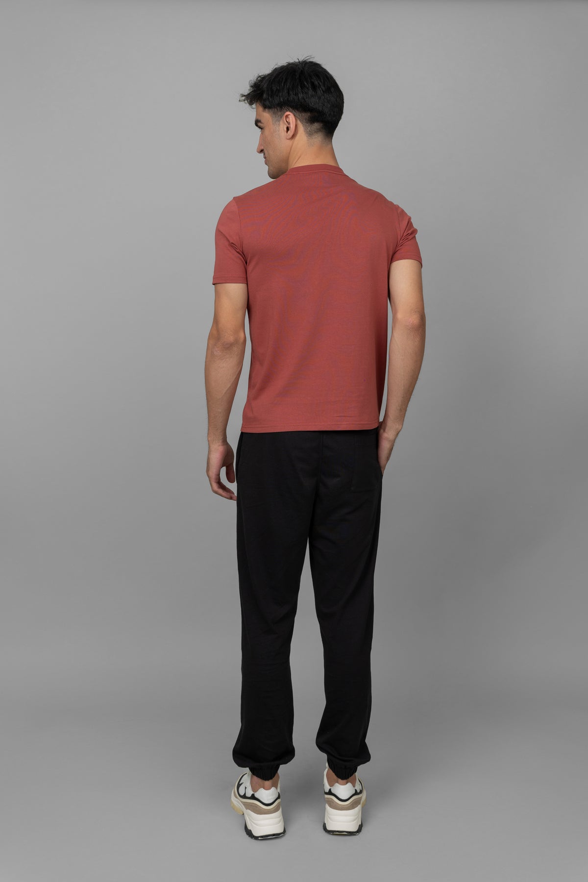 Back view of rust men's essential T-shirt with black pants.
