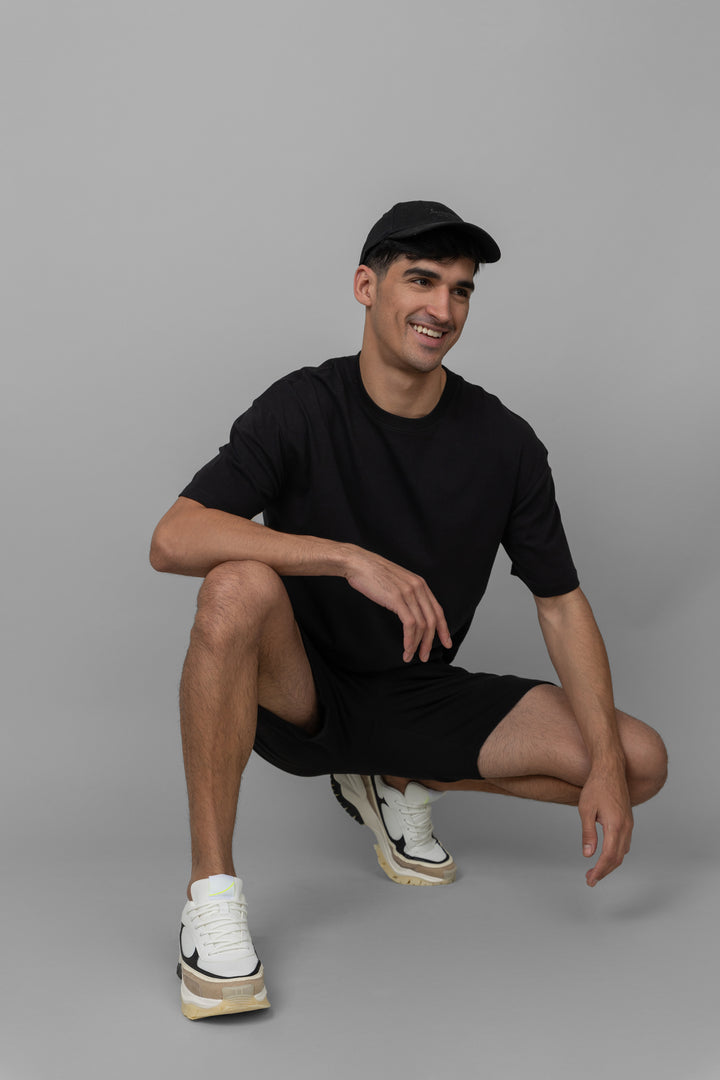 Black men's boxy shorts set worn by a smiling man.