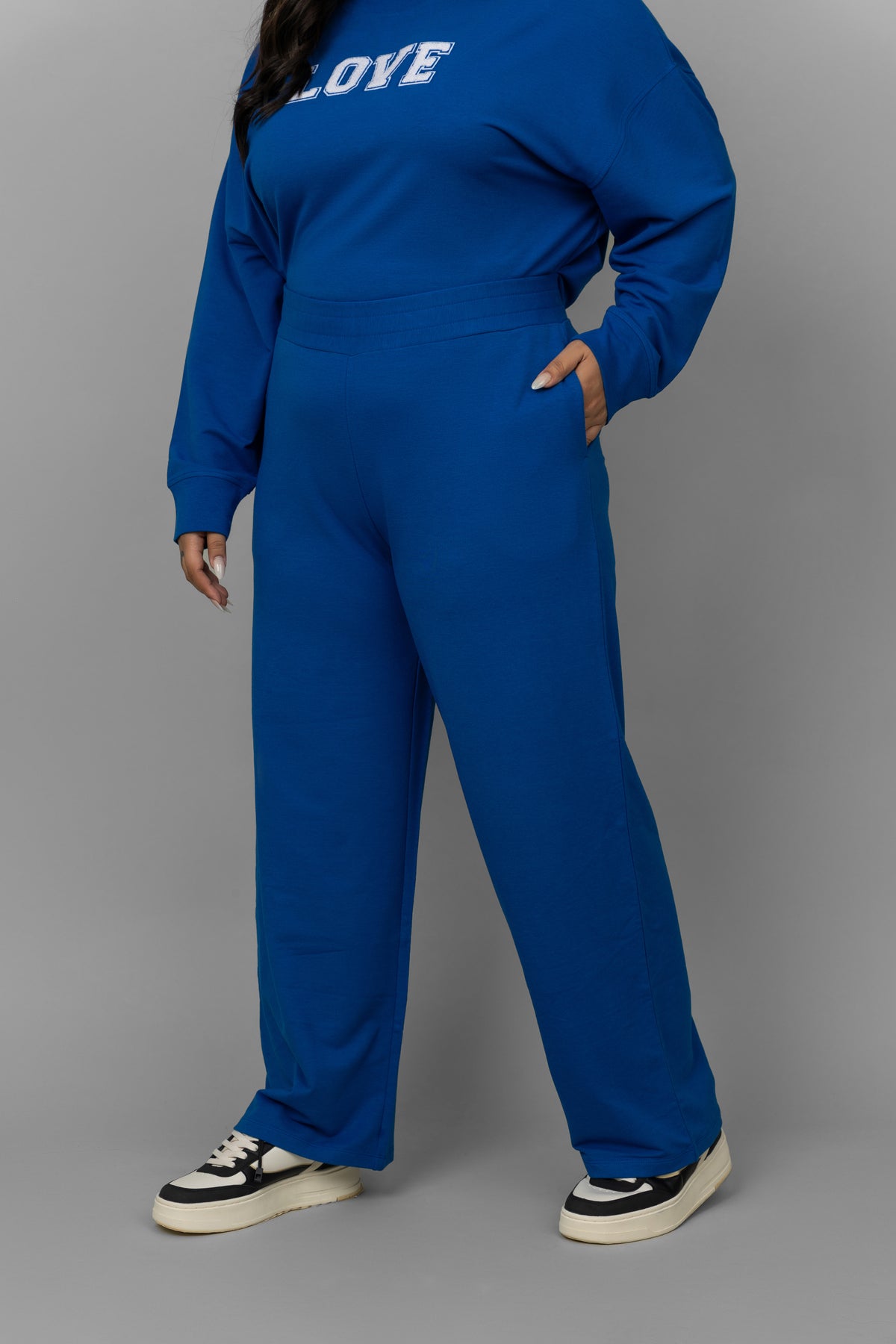 Plus-size model wearing blue bamboo terry travel pants and sneakers.