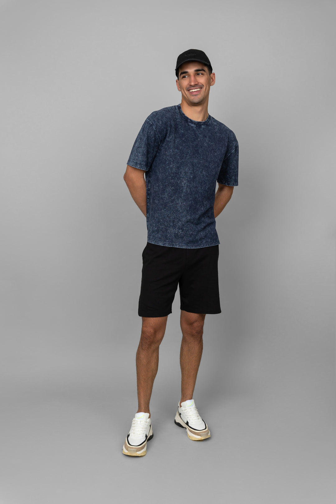 Navy acid wash shorts set on a smiling man in casual attire.