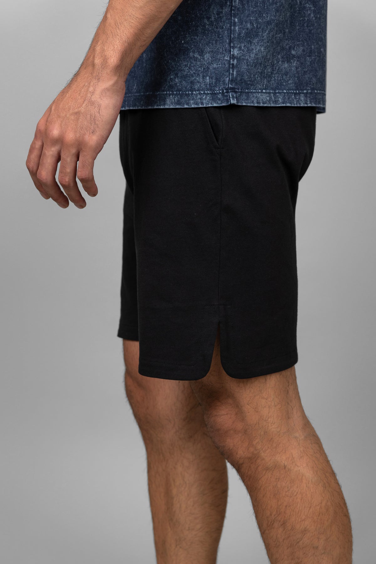 Black men's shorts displayed on a model in stylish outfit.
